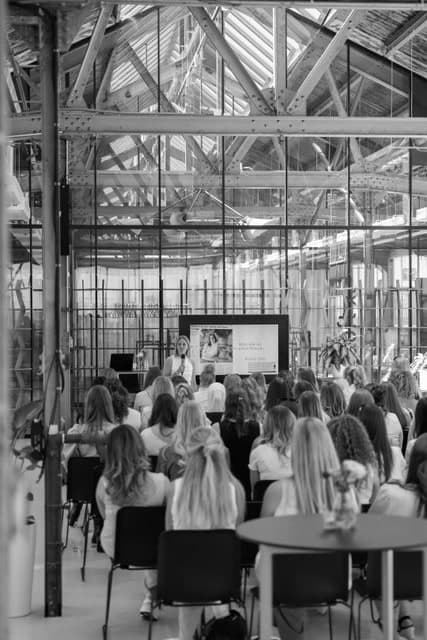 Kim spreekt een zaal met ondernemende vrouwen toe